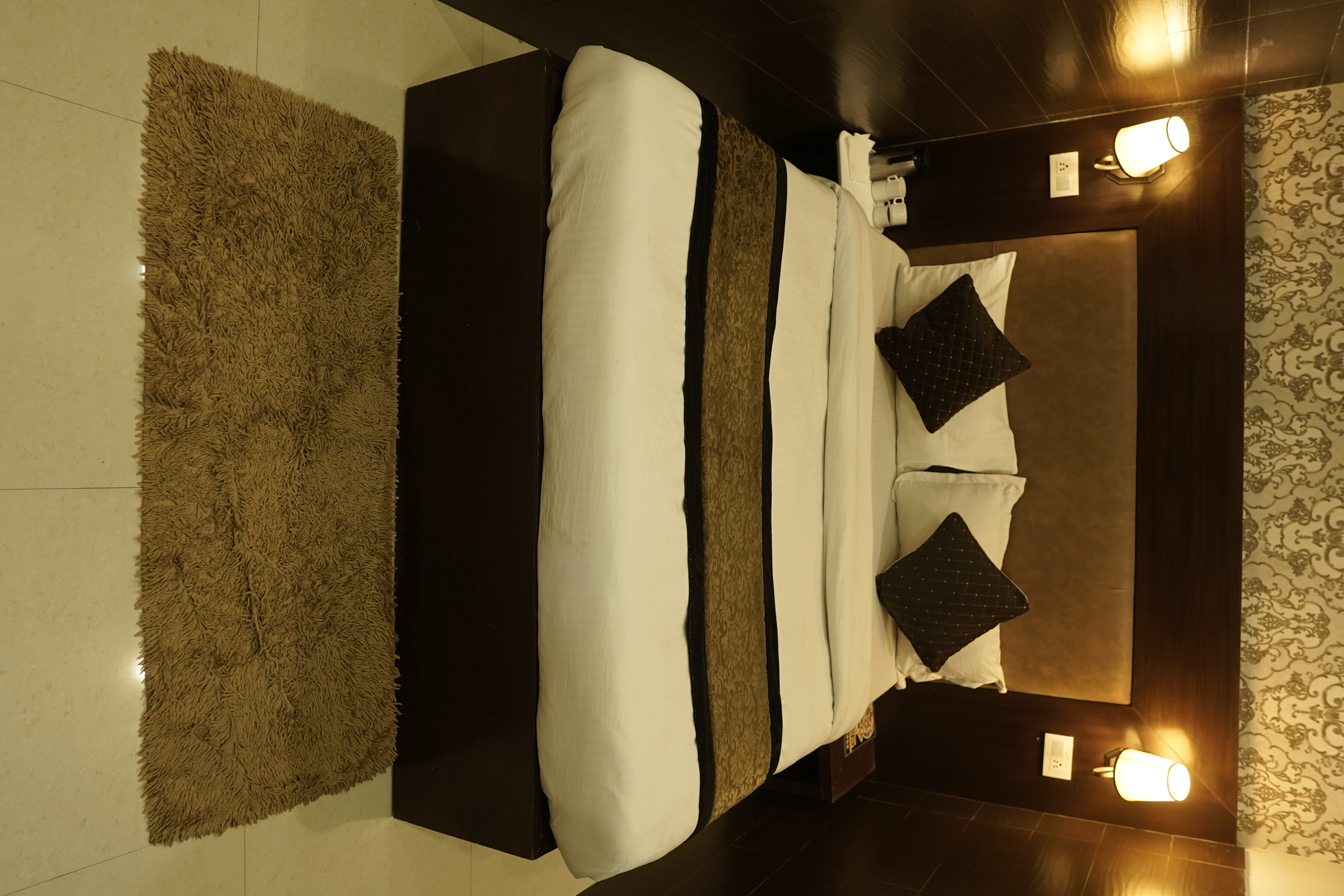 Deluxe Room queen bed with crisp linen and warm lighting